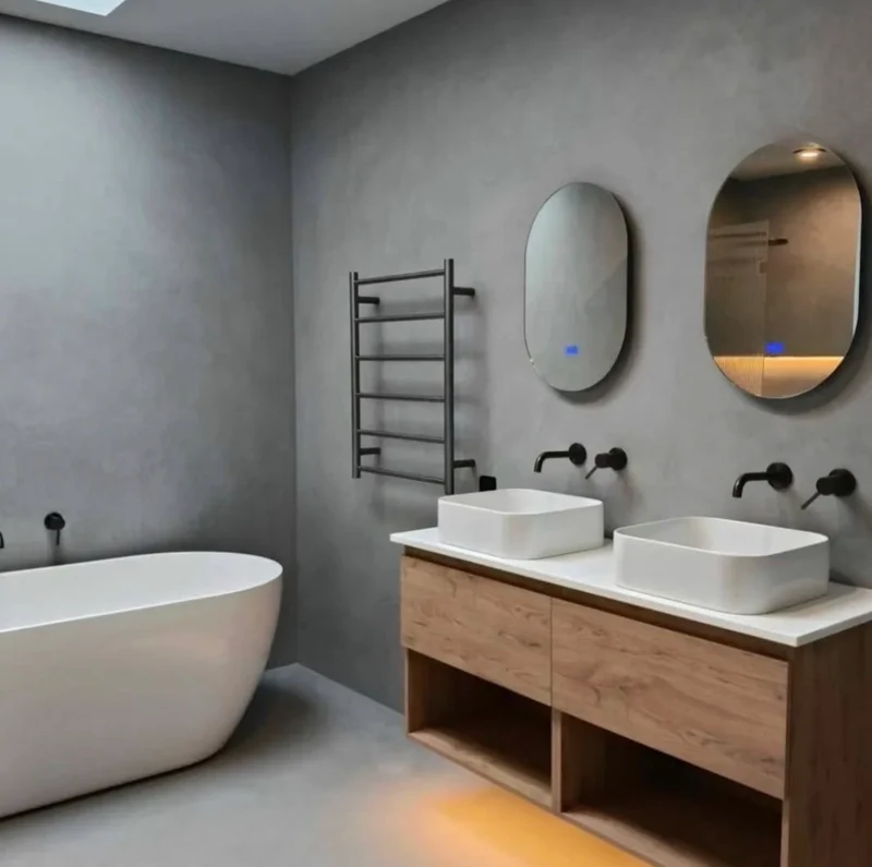 Charcoal grey microcement bathroom in Park City, Utah with oval backlit mirrors, matte black taps and oak vanity