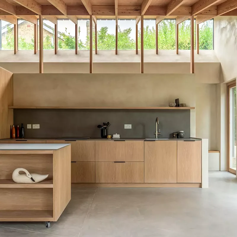Warm greige microcement kitchen walls and pale grey floor in Park City, Utah with clerestory windows, exposed timber roof and oak slab cabinetry