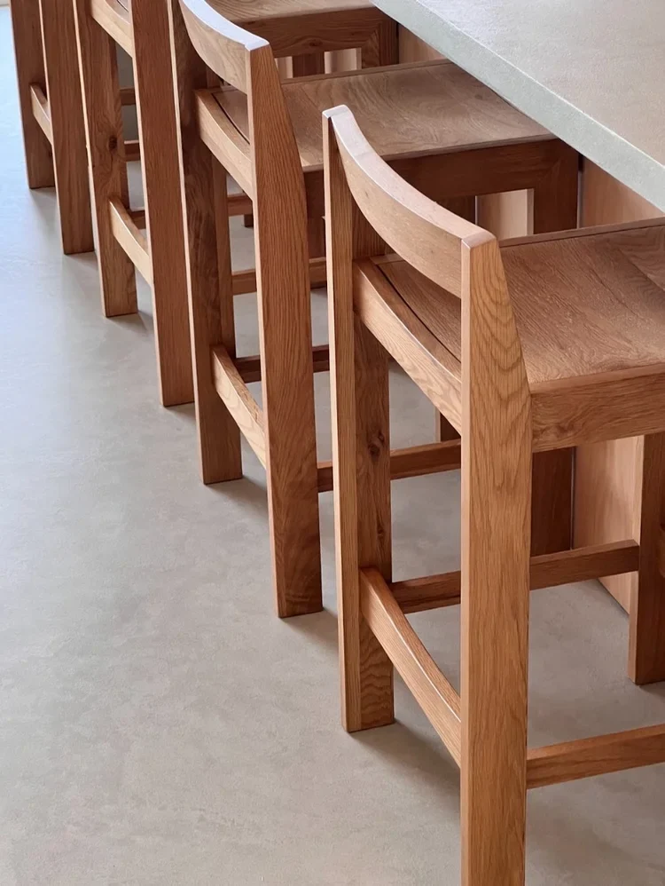 Oyster greige seamless microcement kitchen island floor in Park City, Utah with white oak counter stools and honed stone countertop