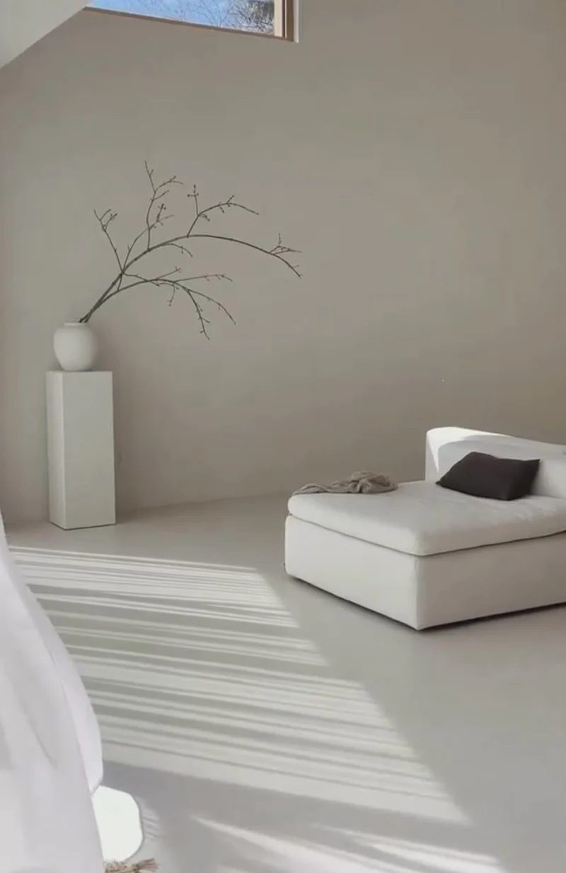 Pale greige microcement bedroom lounge floor and walls in Park City, Utah with striped raking sunlight and white daybed