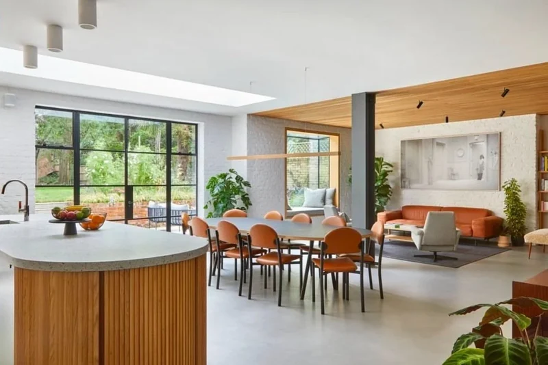 Pale grey seamless microcement open-plan kitchen floor in Park City, Utah with a curved reeded oak island, terrazzo worktop and Crittall glazing