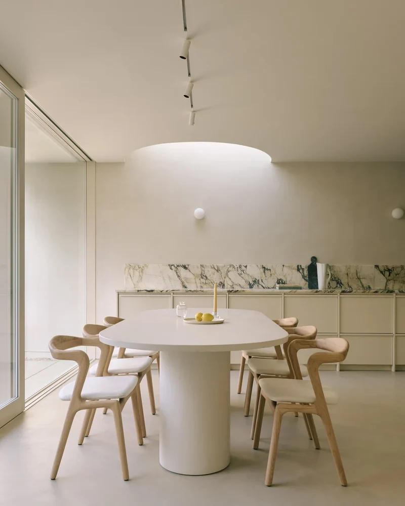 Pale bone seamless microcement kitchen floor and walls in Park City, Utah with curved cove lighting, viola marble counter and cream cabinetry