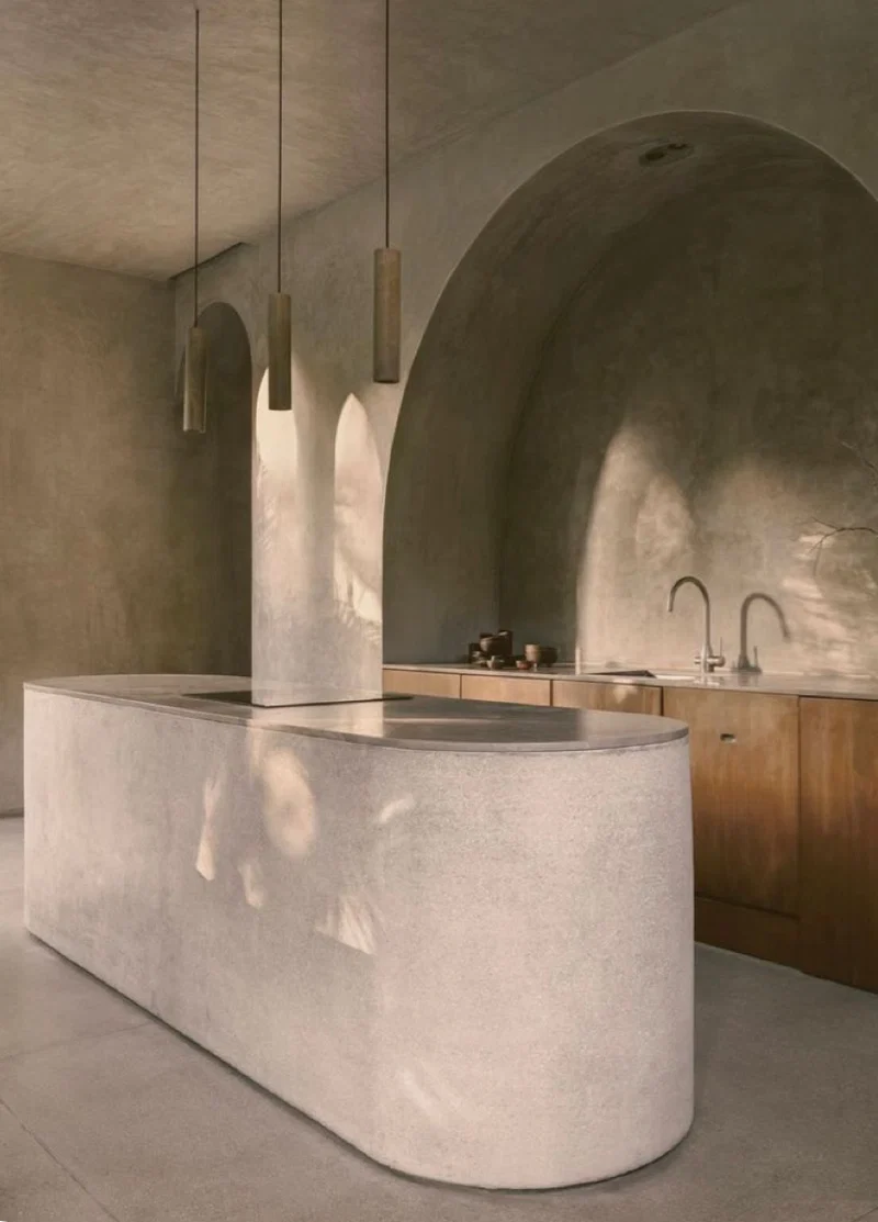 Greige taupe microcement barrel-vaulted kitchen ceiling in Park City, Utah with a curved monolithic island, rounded corners and walnut cabinetry