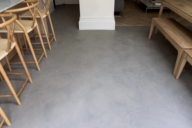 Pewter grey microcement kitchen floor in Park City, Utah with cloudy tonal movement, oak Wishbone bar stools and herringbone parquet transition