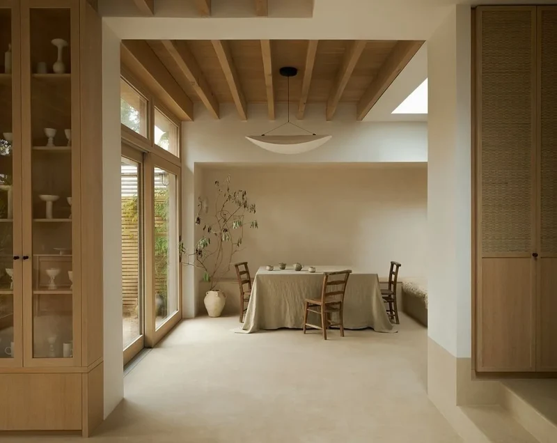 Warm oat bone microcement dining room floor in Park City, Utah with exposed oak joist ceiling, skylight and linen-draped table